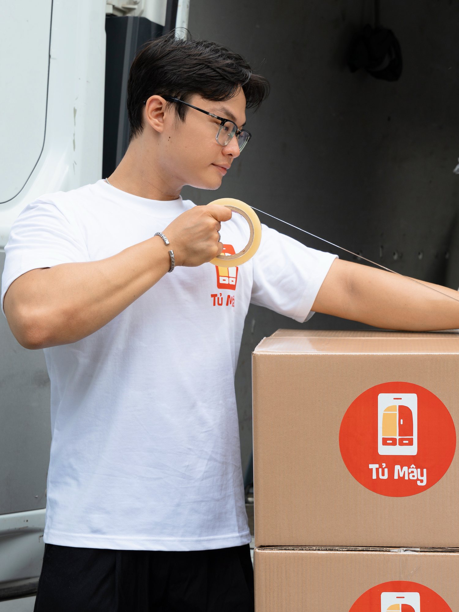 A Tủ Mây crew member taping a box shut before it is loaded