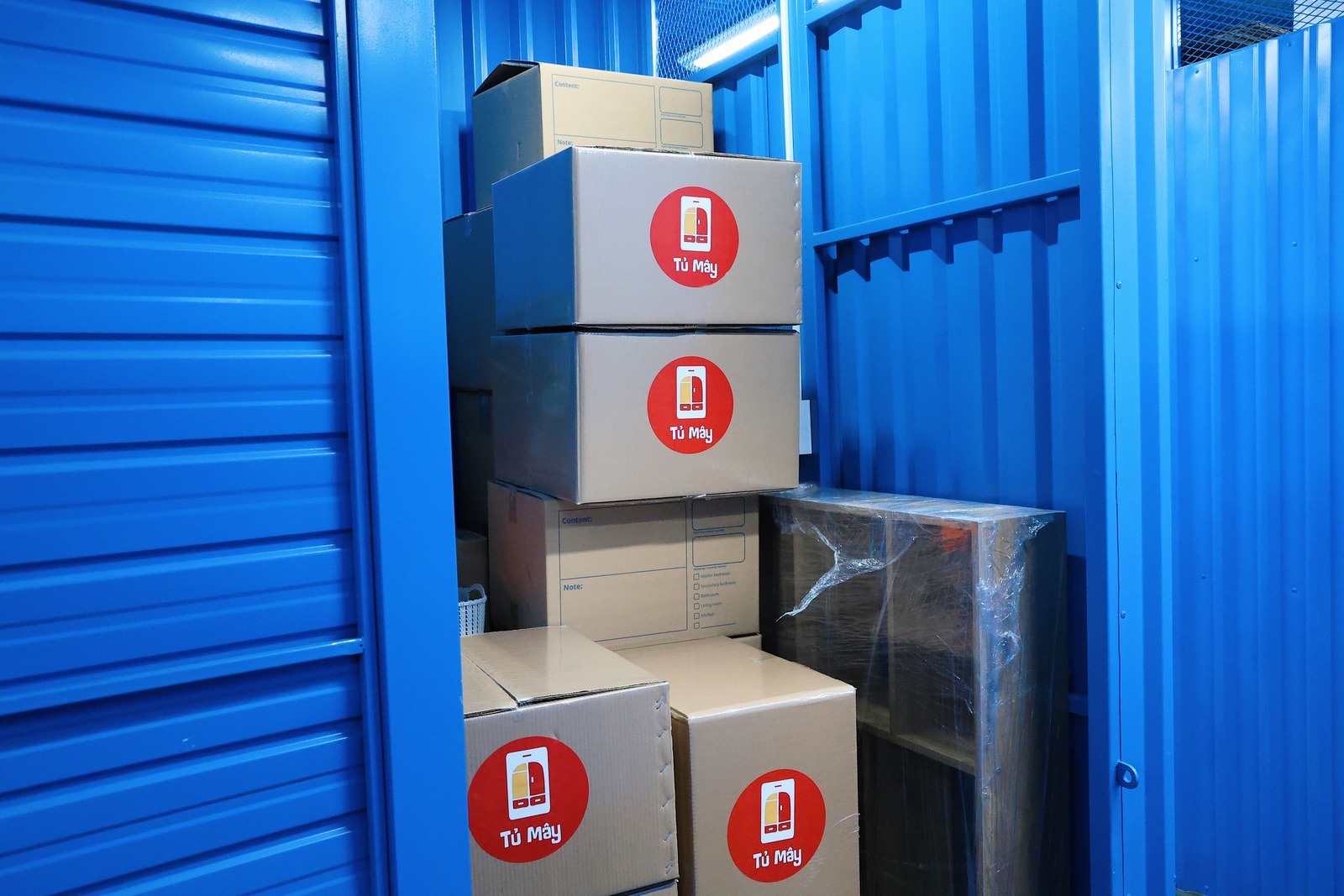 Inside a unit: stacked Tủ Mây boxes and wrapped furniture