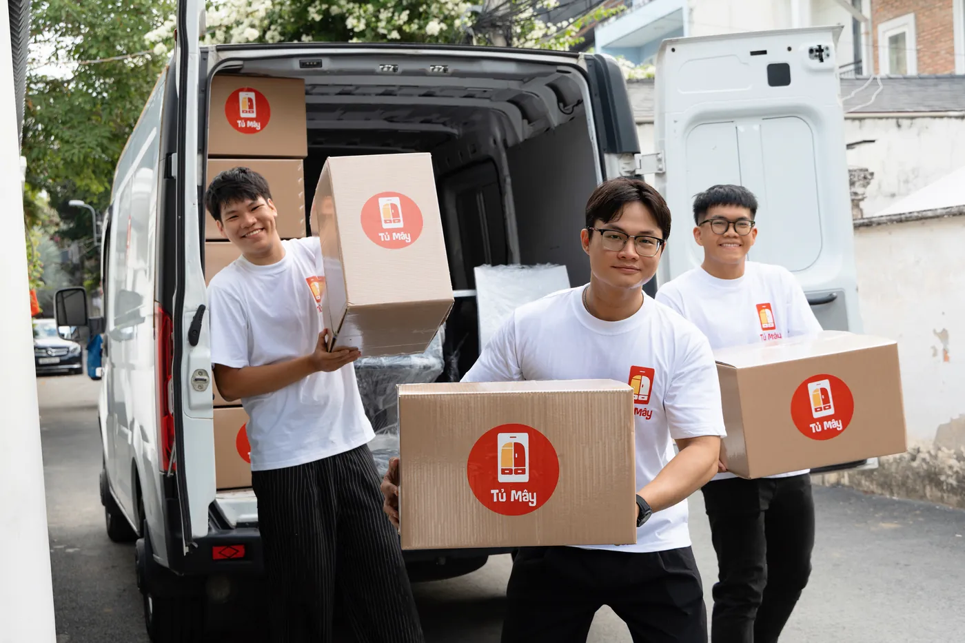 Ba nhân viên Tủ Mây khiêng thùng từ xe trên một con đường ở TP.HCM