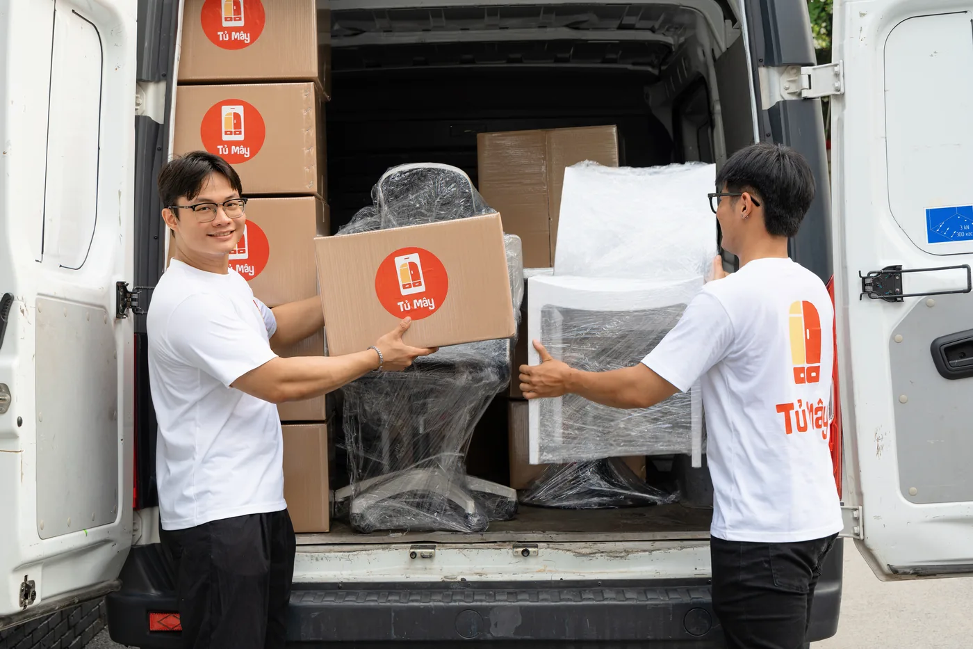 Crew members passing a wrapped chair into the van