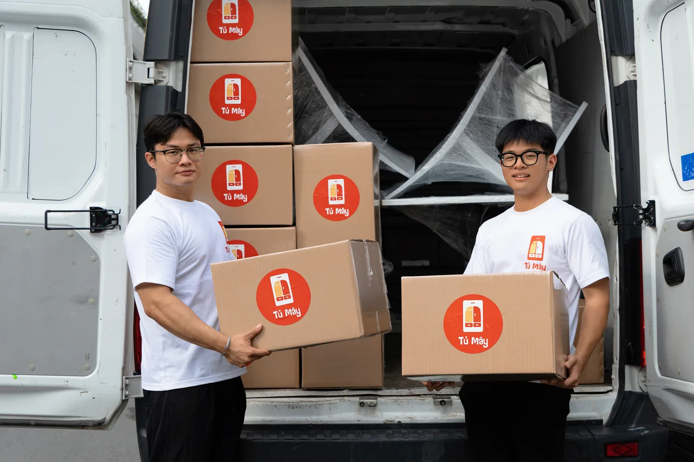 Two crew members with boxes and wrapped items in the van