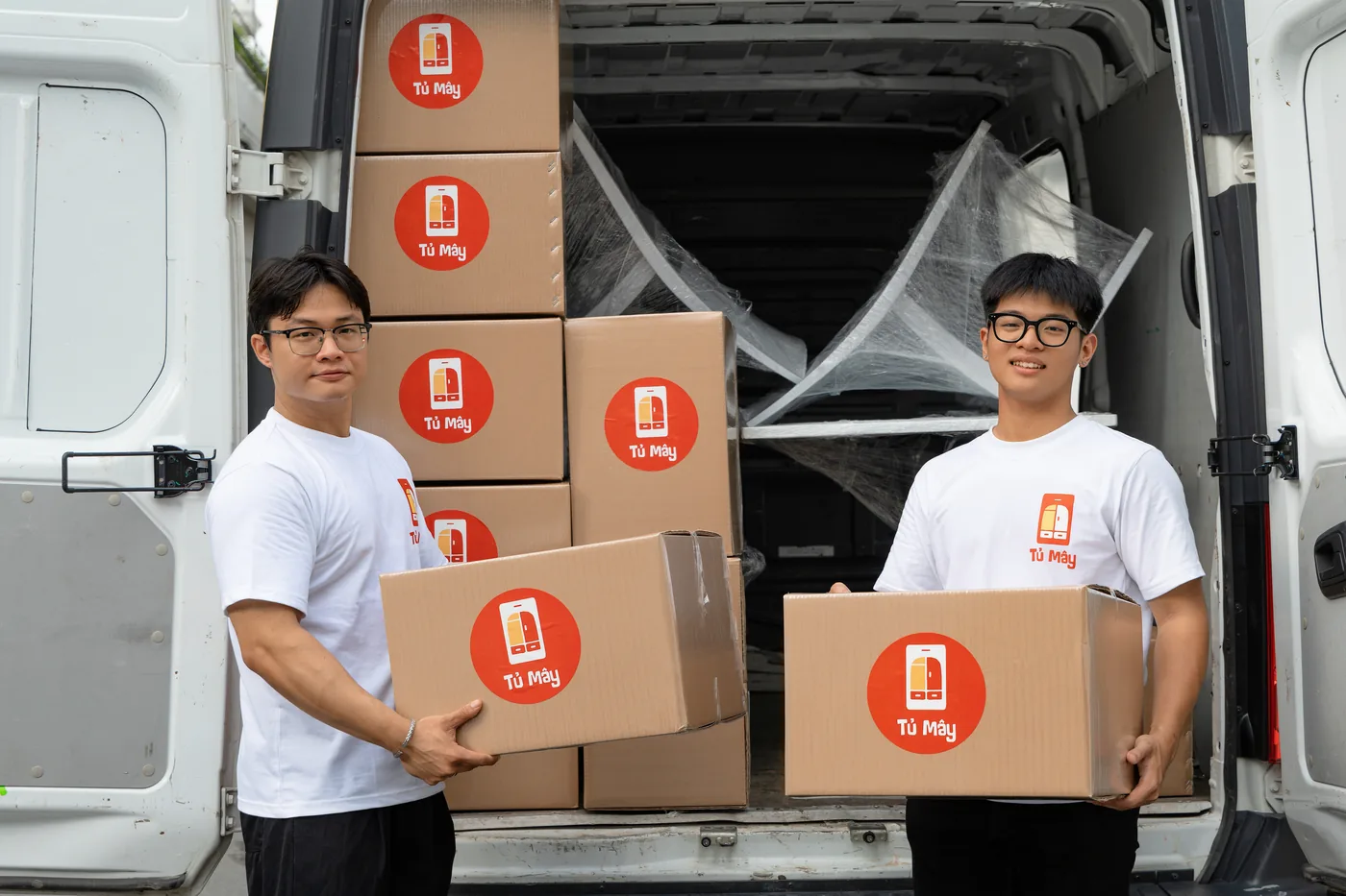 Two crew members holding Tủ Mây boxes