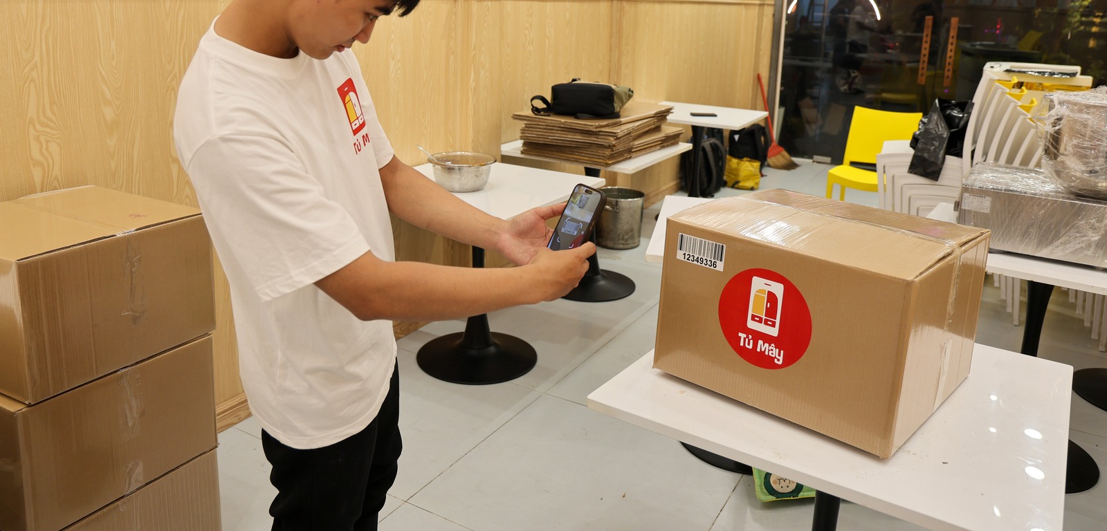 A Tủ Mây crew member scanning the barcode on a sealed box with a phone