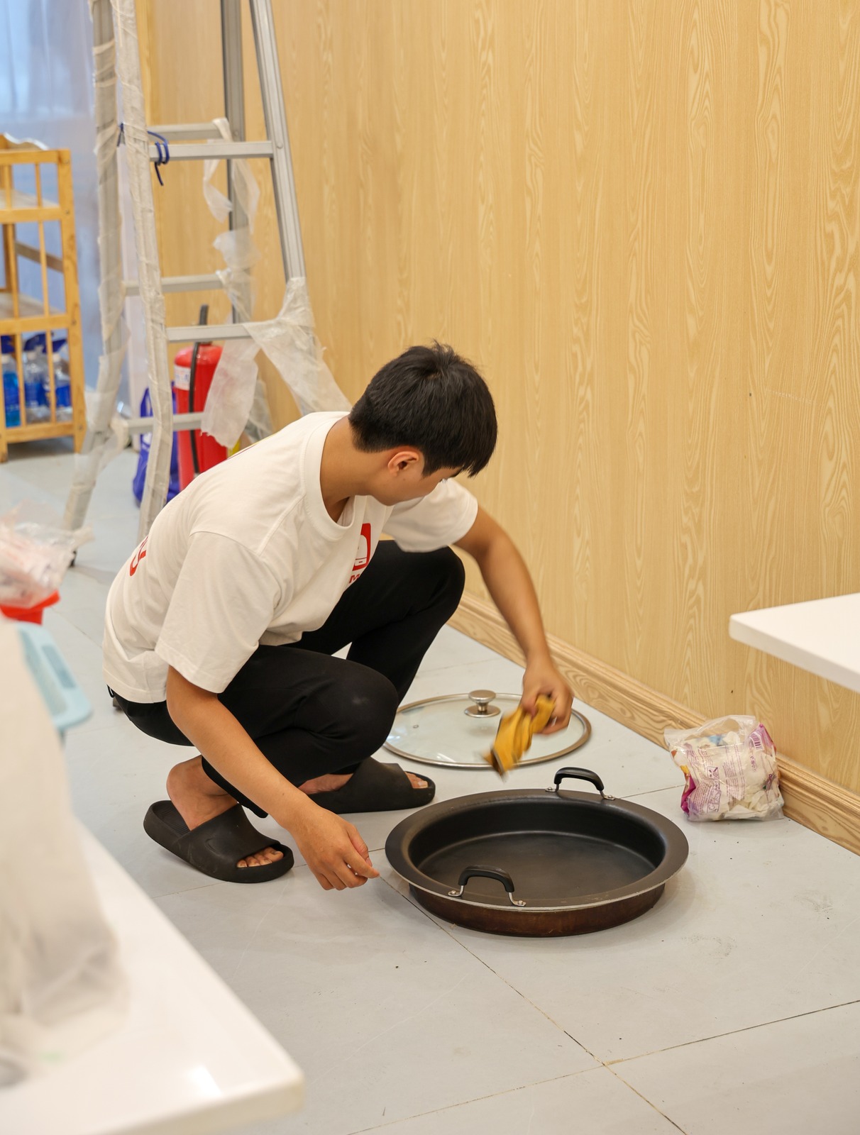 A crew member cleaning a pan and its glass lid before it is packed