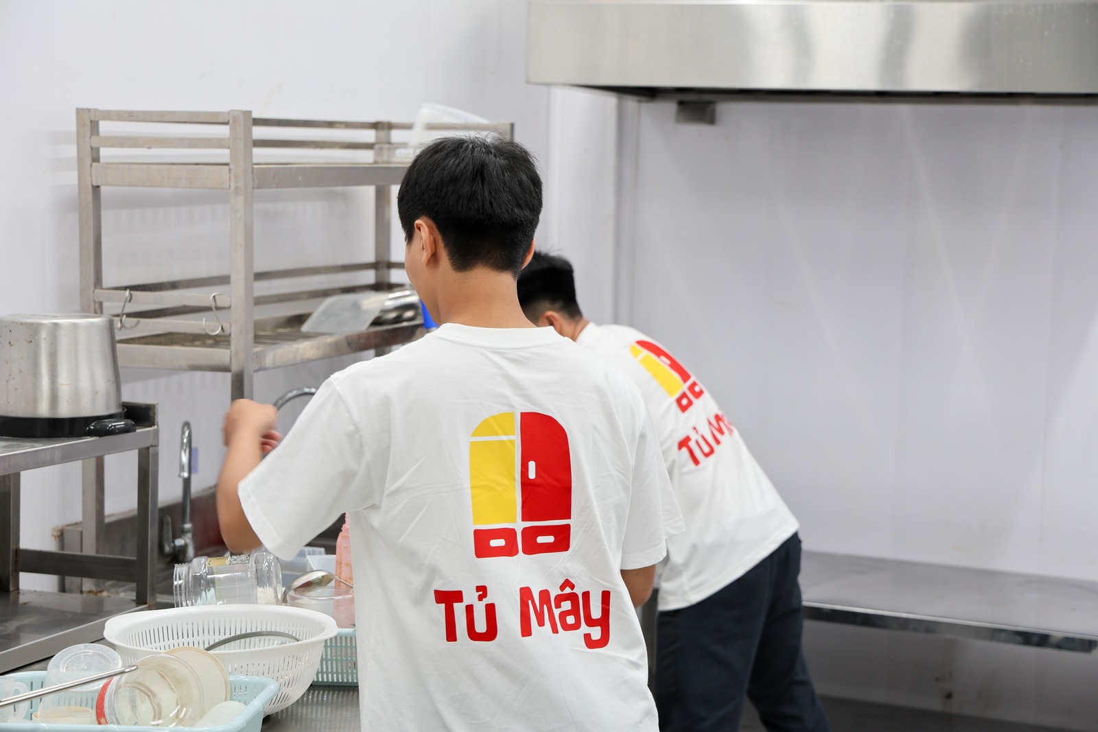 Two Tủ Mây crew members working in the stainless kitchen