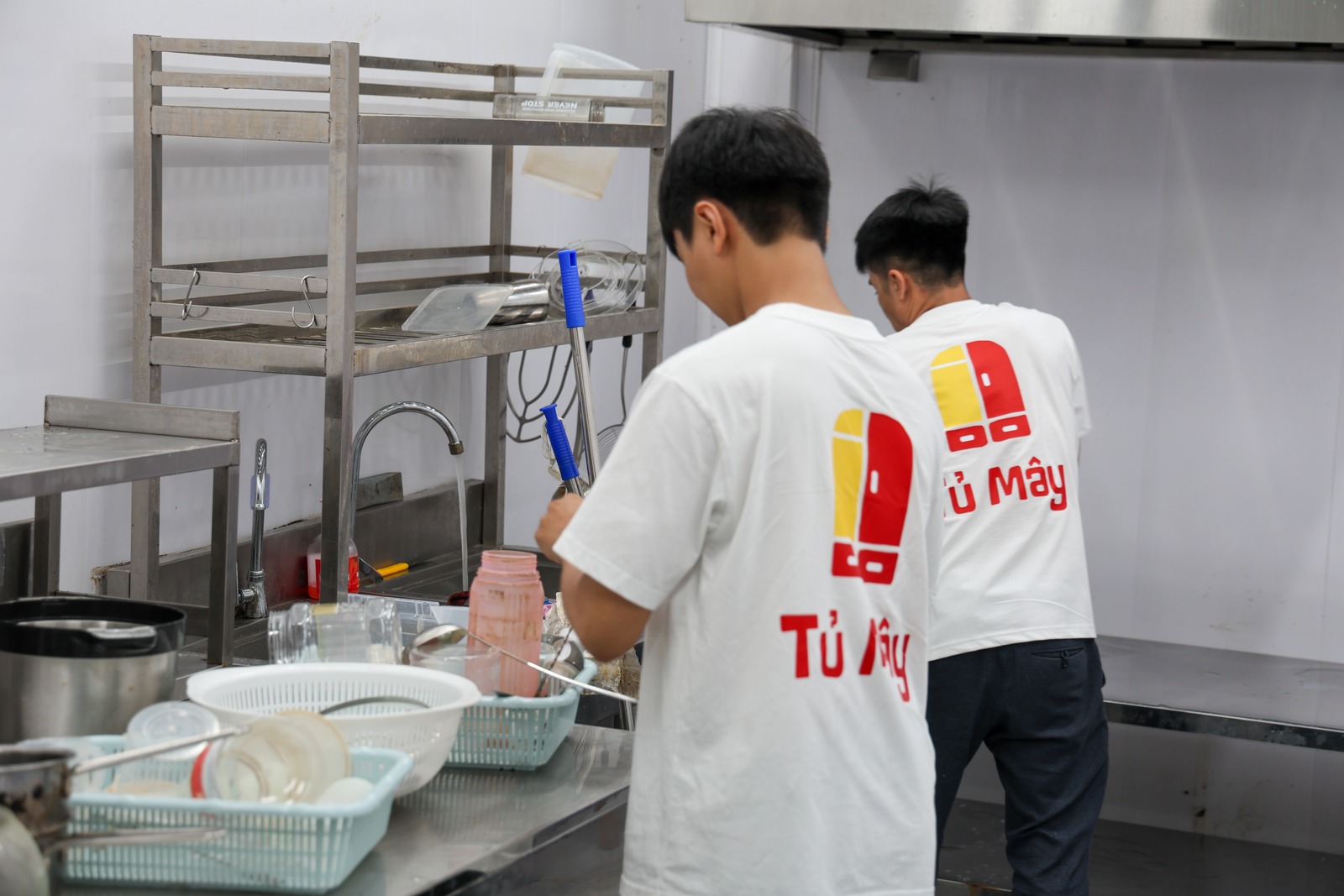 A crew member washing kitchen tools and racking them to drain
