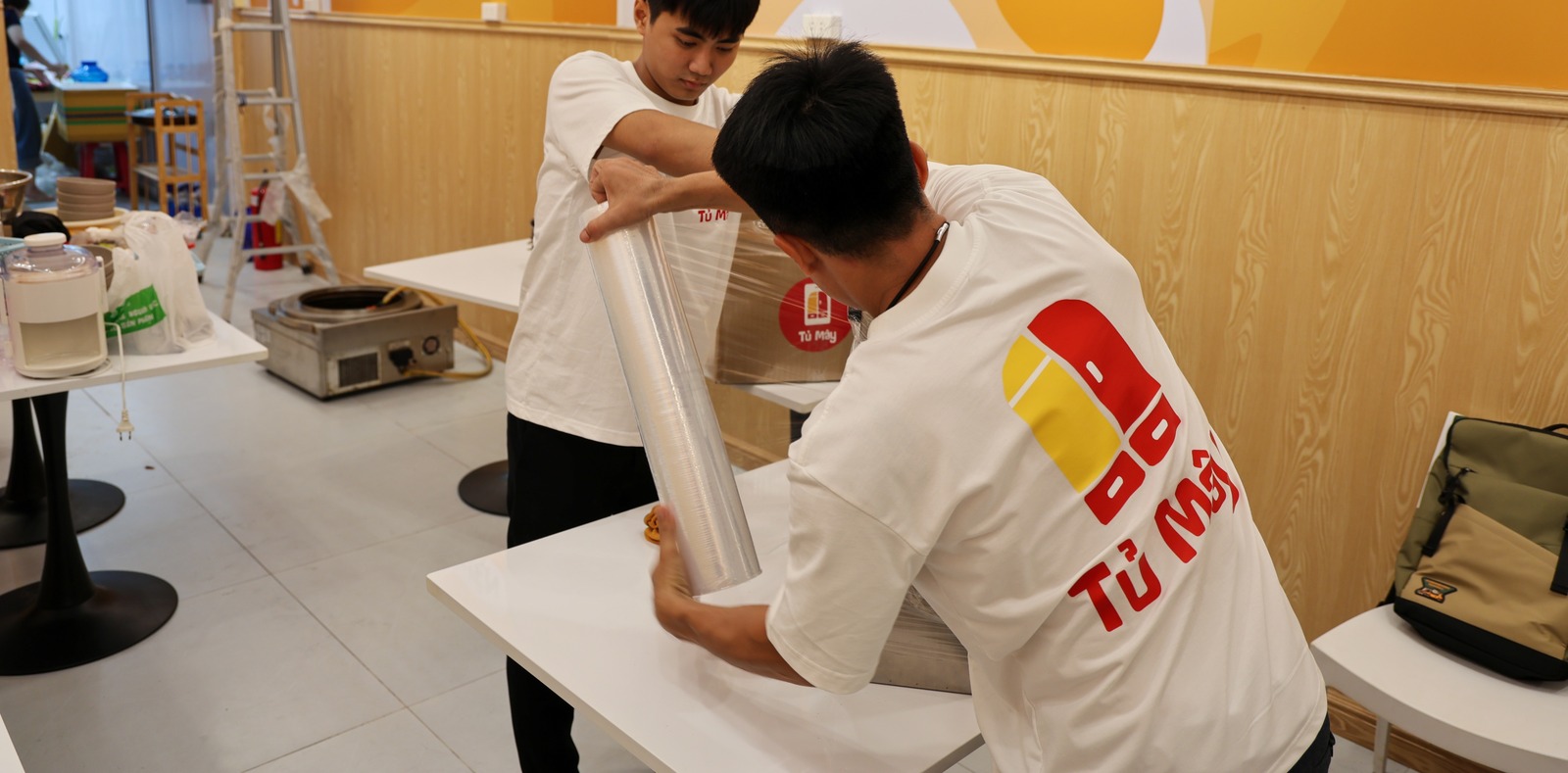 Nhân viên kéo màng PE quanh một máy bếp trên bàn
